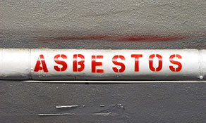 A white pipe with ASBESTOS written on it in red capital letters.