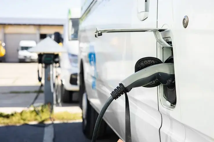 A close up of an electric van plugged into an on-street charging point.