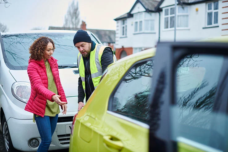 A man and a woman discussing a minor collision between a van and car.