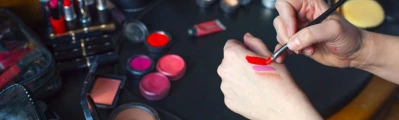 A make-up artist uses a small brush to test colours on the back of her hand.