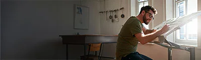 side view of a male architect wearing glasses working on a design at work.