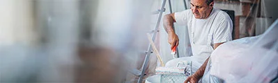 a professional painter preparing to decorate a room with dust sheets and a ladder in the background.