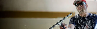 close-up of a window cleaner using a squeegee to clean windows.