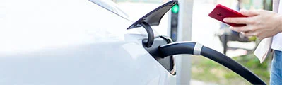An electric van driver uses their smartphone to initiate charging at a charge point.
